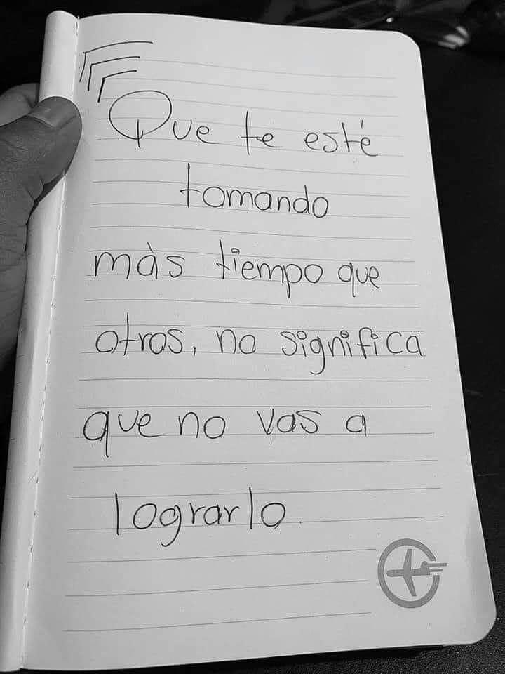 A hand holding open a notebook to a page handwritten in Spanish, reading "Que te esté tomando más tiempo que otros, no significa que no vas a lograrlo."
